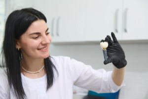 young woman holding dental implant mockup, artificial tooth roots into jaw canal. dental treatment concept